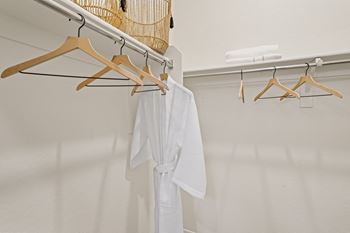 A white robe is hanging on a wooden hanger.